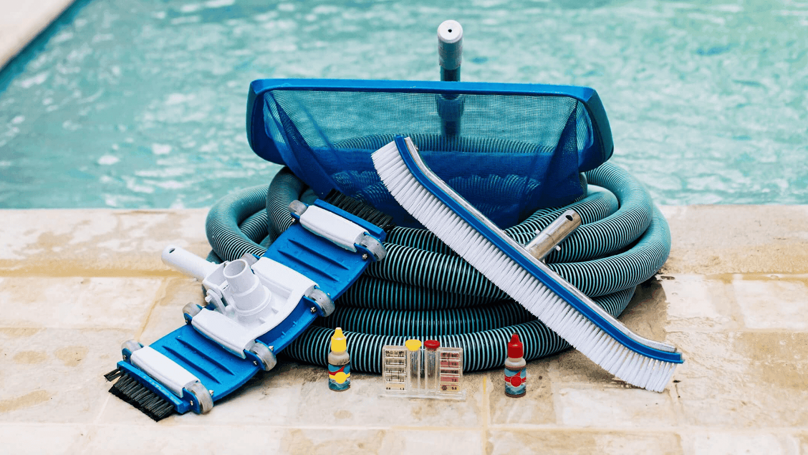 Essential tools for vinyl liner maintenance including a soft brush, skimmer, vacuum, and water test kit