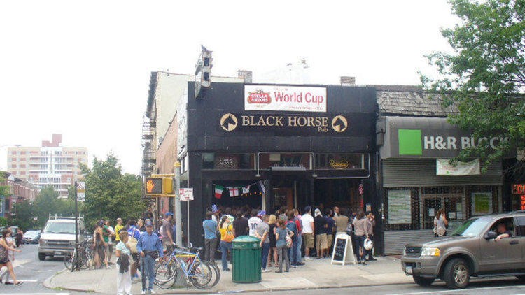 Image of a bar in NYC with crowd around it