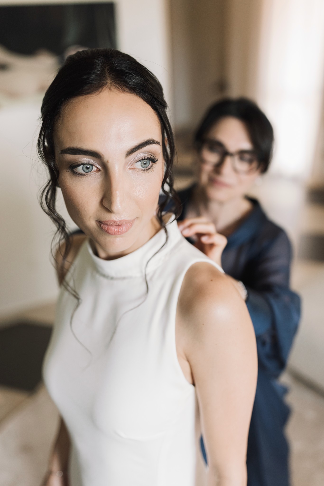 Sposa in abito bianco durante i preparativi del matrimonio al Parco di Montebello, lo sposo sfocato alle spalle
