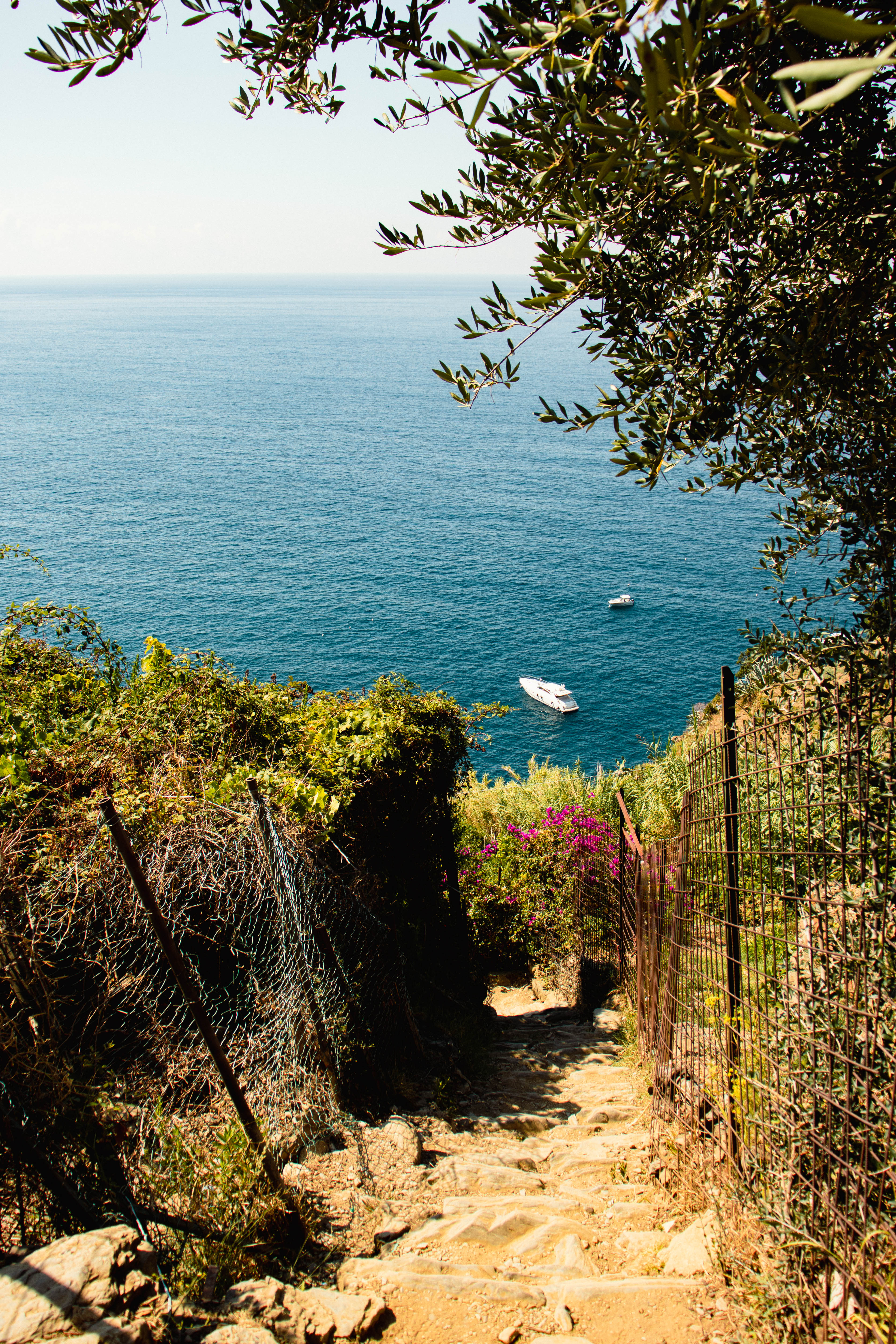 A rustic stone stairway leading down to a blue ocean, representing the step-by-step physical training path to male pelvic health and recovery in Oak Park, IL.