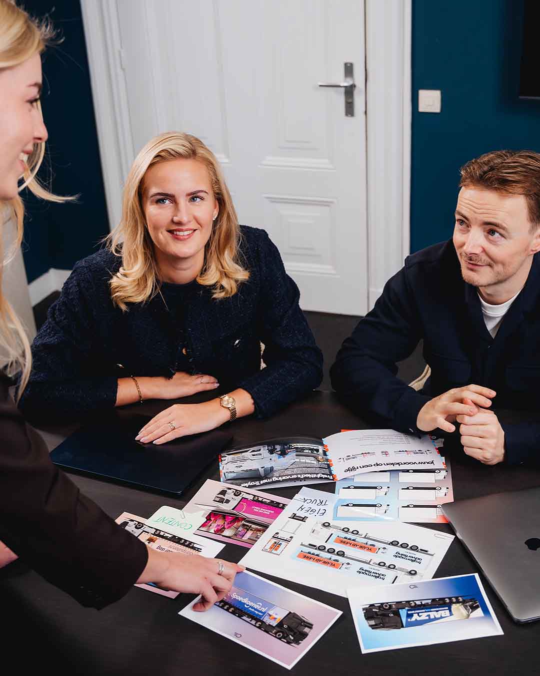 foto van een vrouw en man die kijken naar een andere vrouw die uitleg geeft