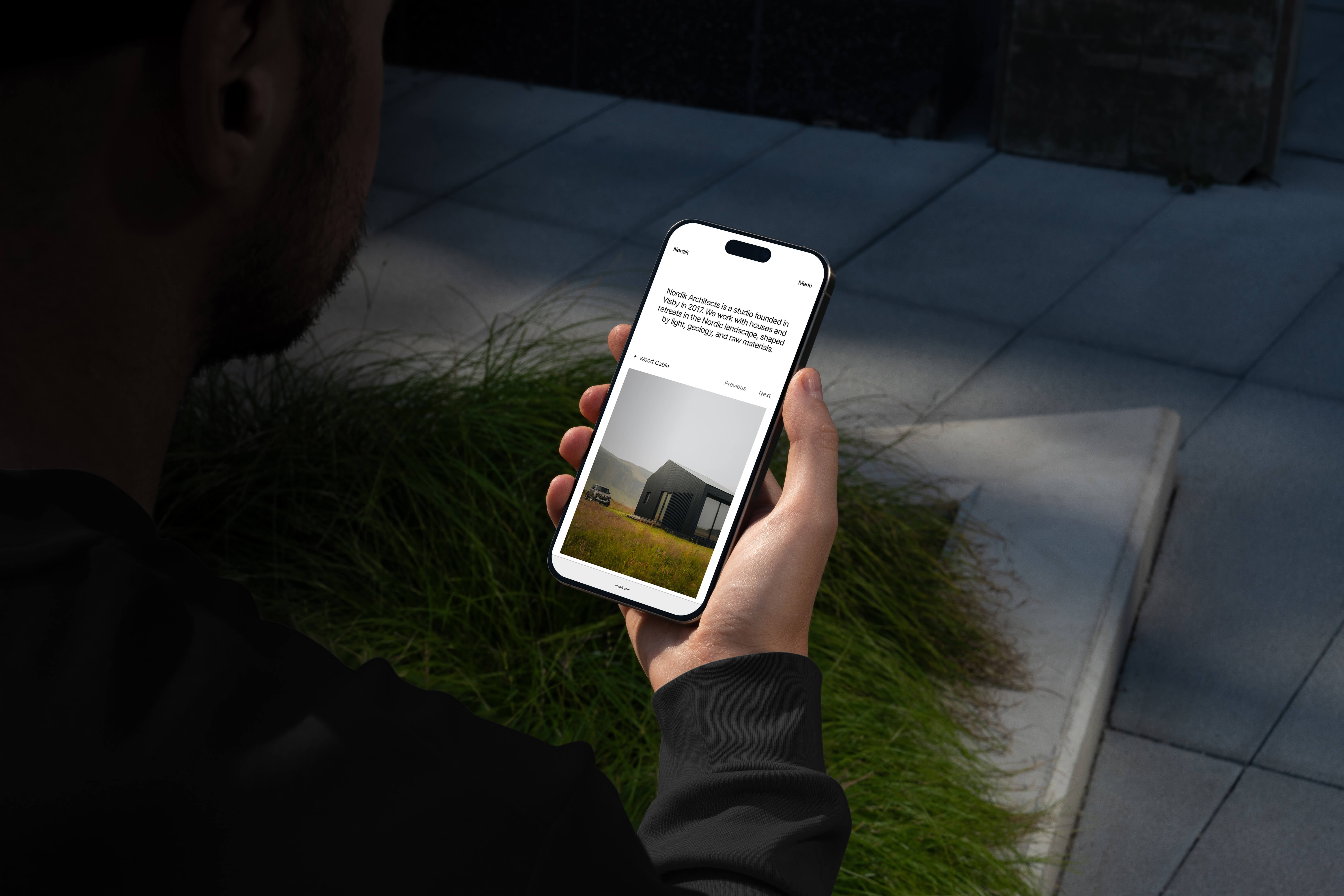 Man holding a phone in a Scandinavian environment, showcasing a minimalist website done by Lucas Eriksen