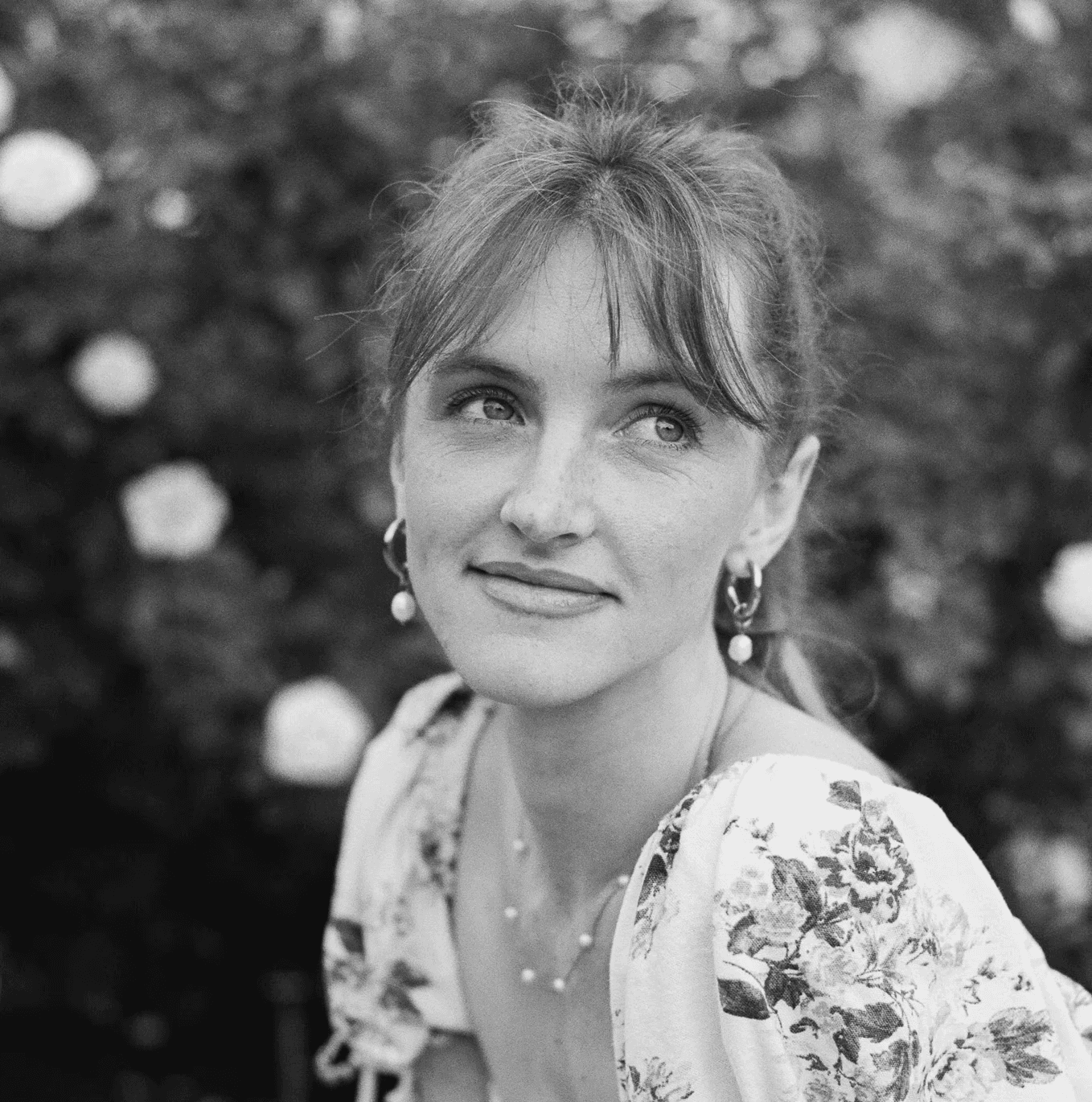 Portrait of a laughing person with curly hair wearing a white shirt