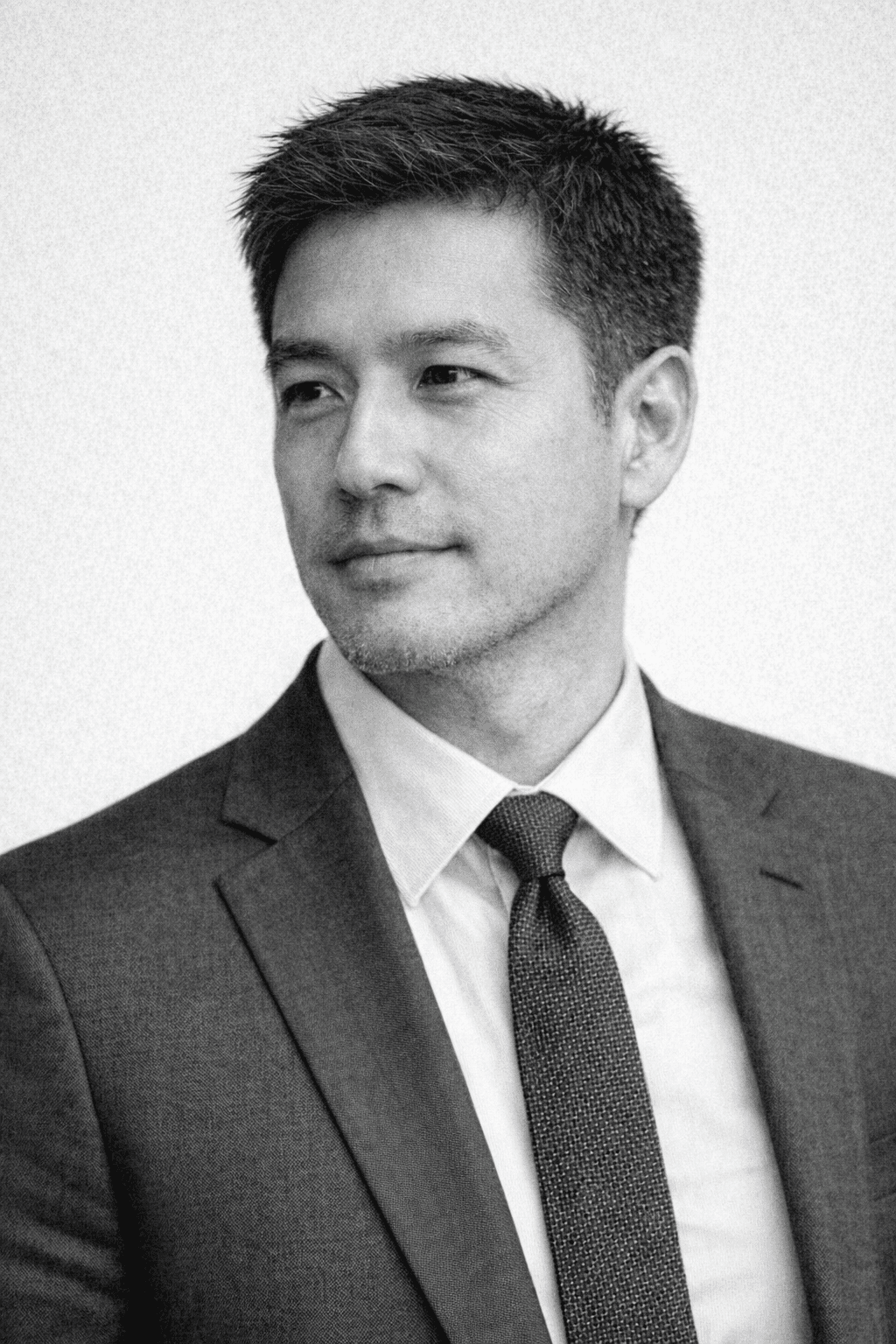 Portrait of a woman with straight long hair, in a dark t-shirt, set against a neutral backdrop.