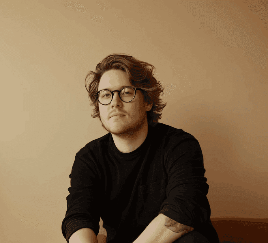 Black-and-white portrait of a man wearing glasses and a dark sweater