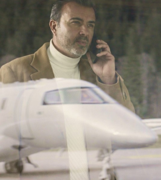 Man on the phone looking at a Pilatus PC-24 aircraft