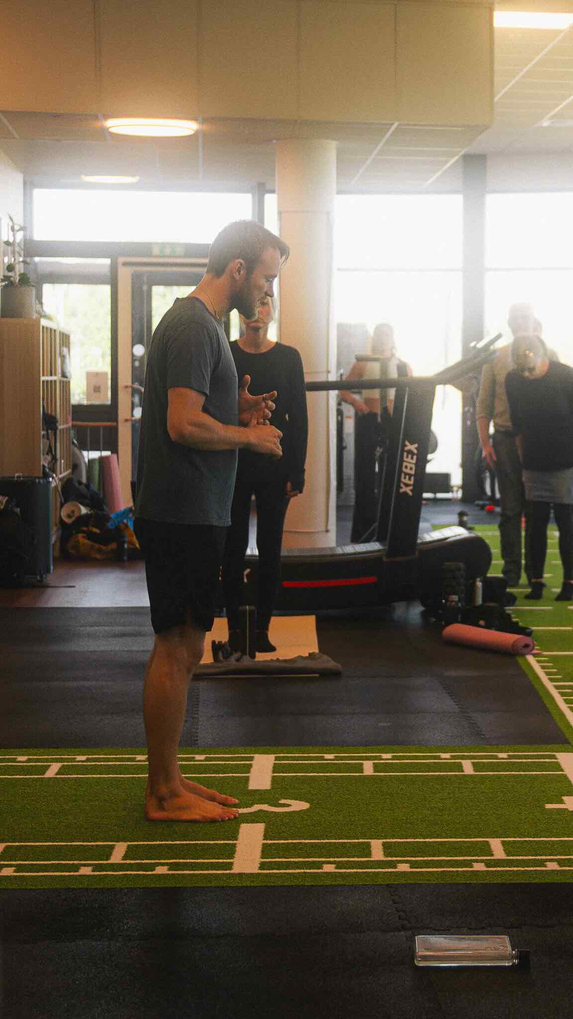 A young male soccer player in a neon green jersey dribbling a ball on an artificial turf field.