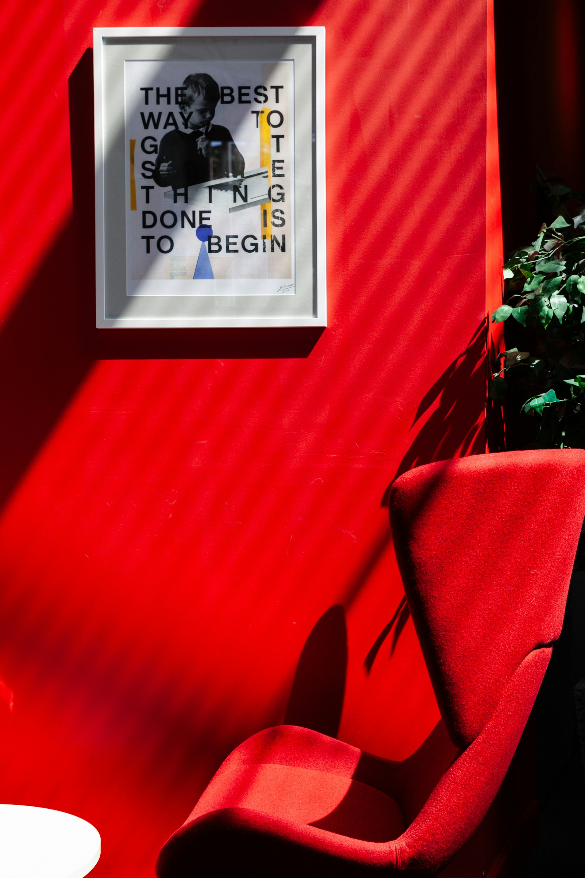 Red studio wall with a framed typographic poster and a vermilion chair