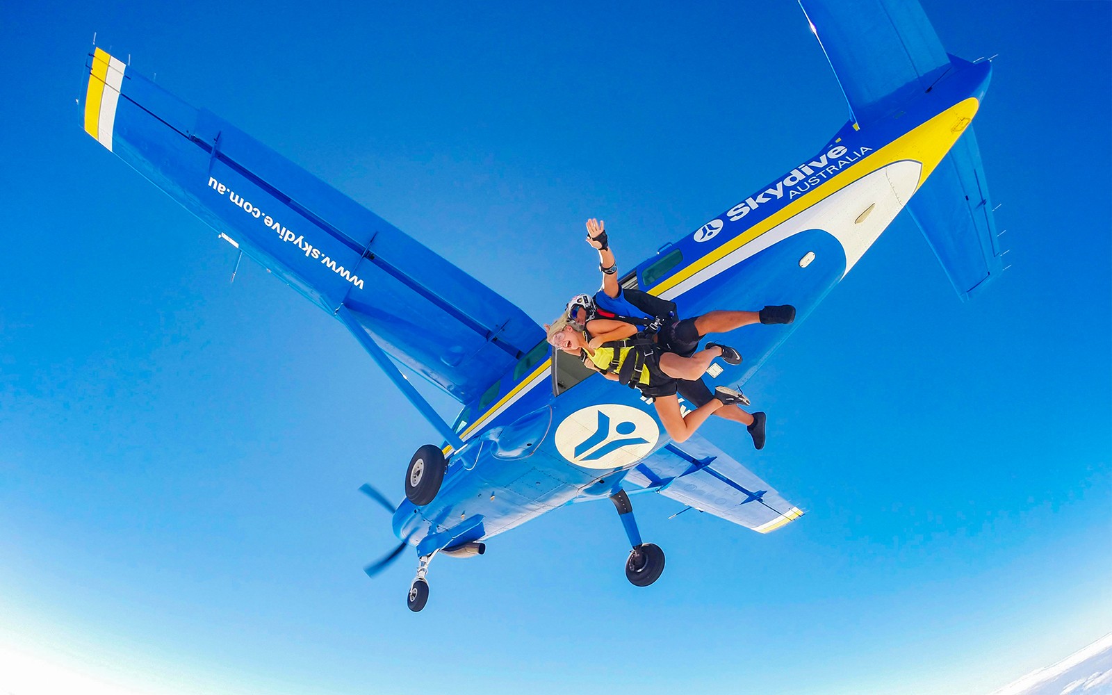 צניחת טנדם מעל חוף איירלי עם מדריך וצונח יוצאים מהמטוס.