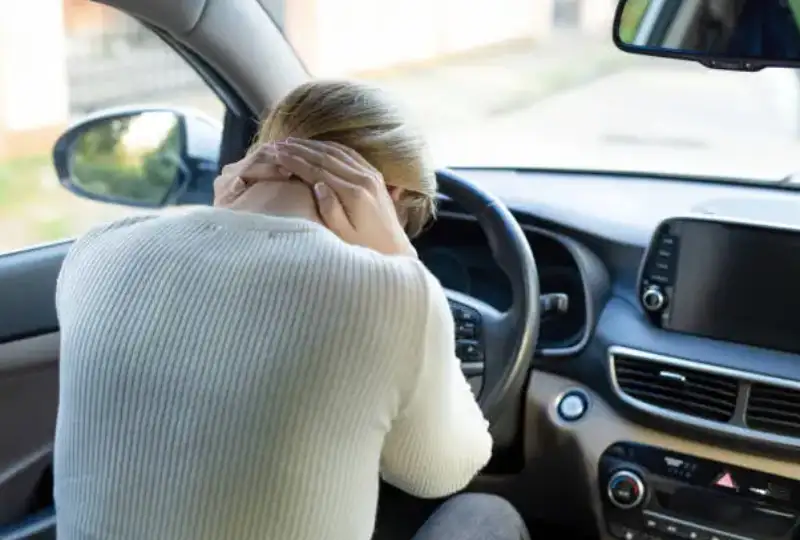 Person holding neck after a car accident in Draper Utah, seated in a vehicle