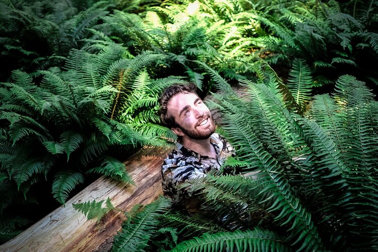 Headshot of Sean leaning against a log