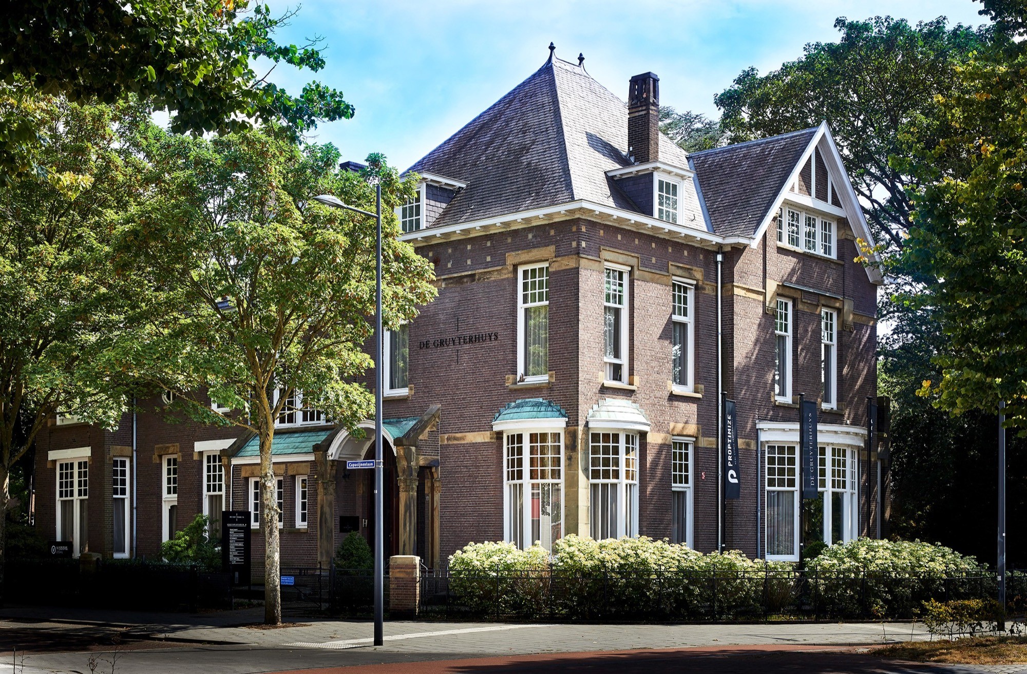 Monumentale bakstenen villa De Gruyterhuys met leien dak, omgeven door bomen