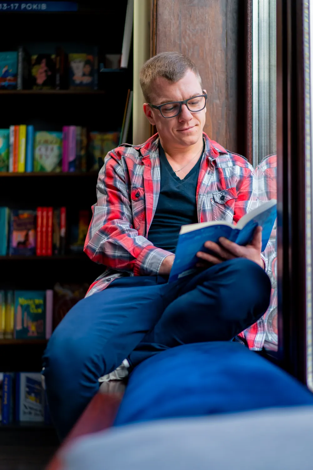 man sat by window reading a book