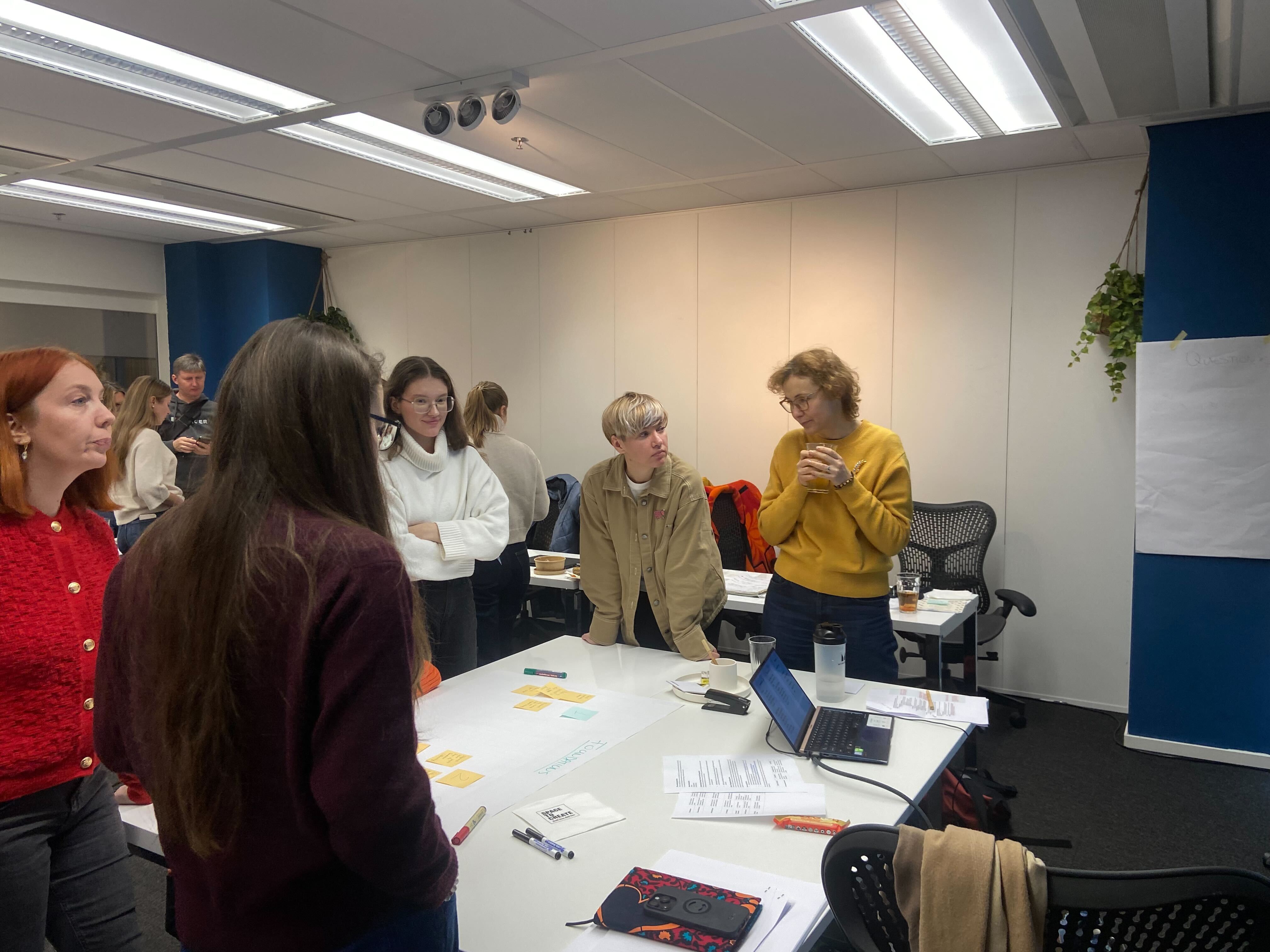 Group of participants standing and engaging in discussion during the Civil Society Hub’s Expert Pool Session on Fundraising, in a collaborative meeting room setting.