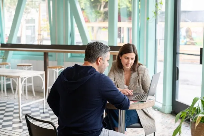 Conseillère et client échangeant autour d’un ordinateur portable.