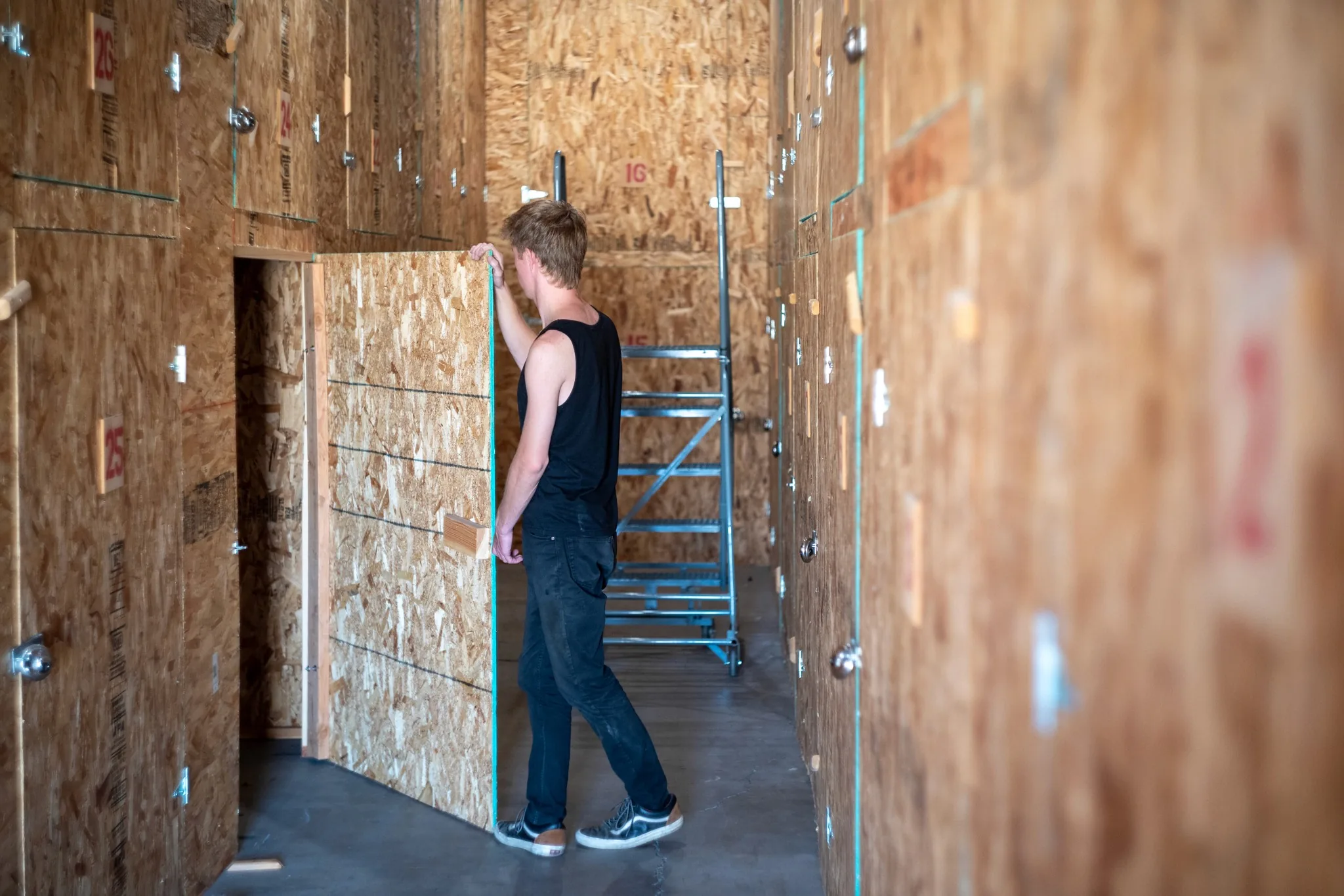 Student sweeping the inside of a wood-paneled storage locker