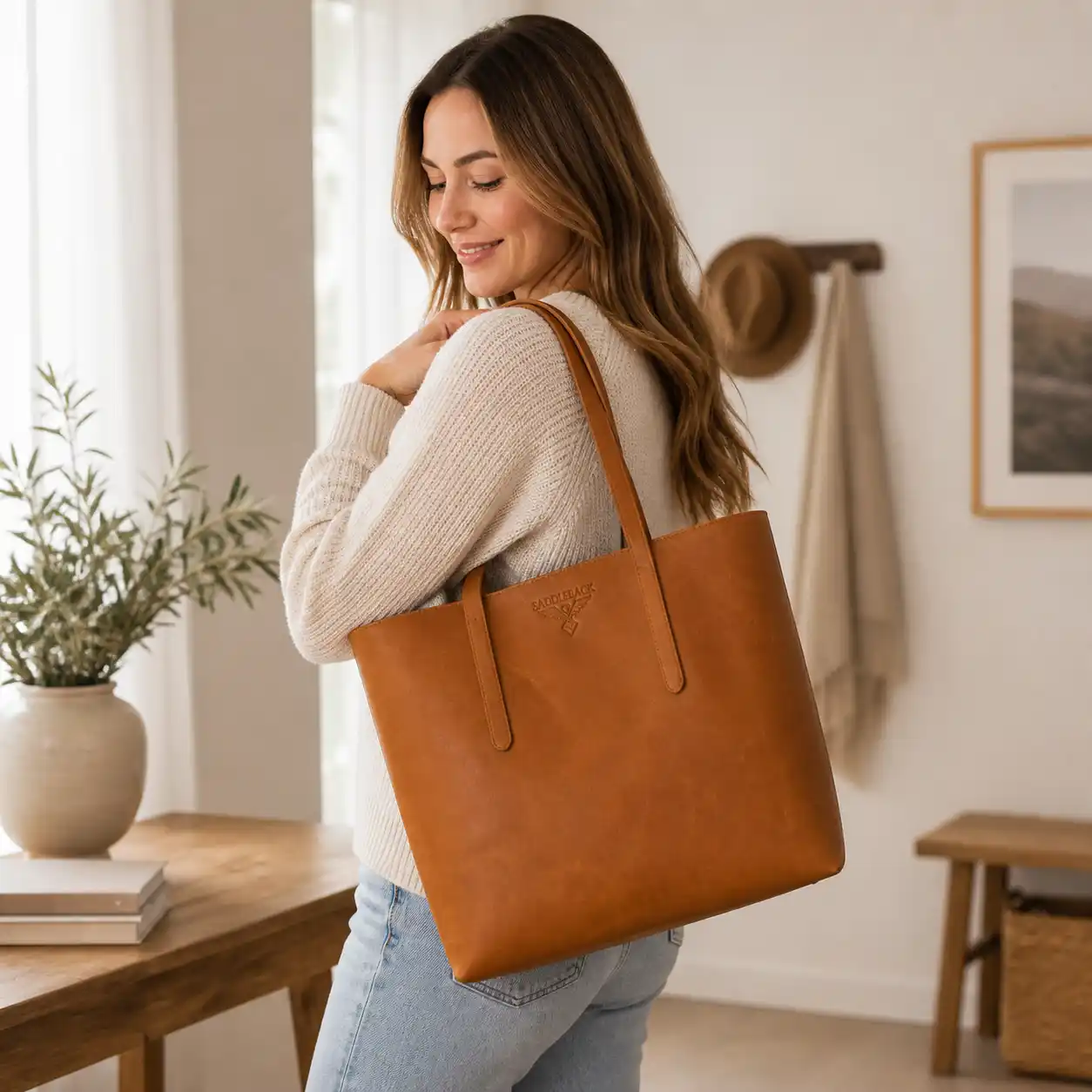 Kvinne som bærer en stor totebag i brunt skinn.
