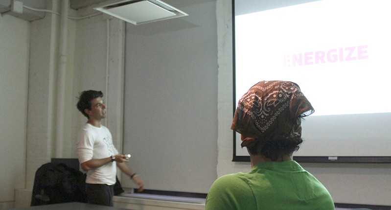 A photo of two people staring at a screen projector.