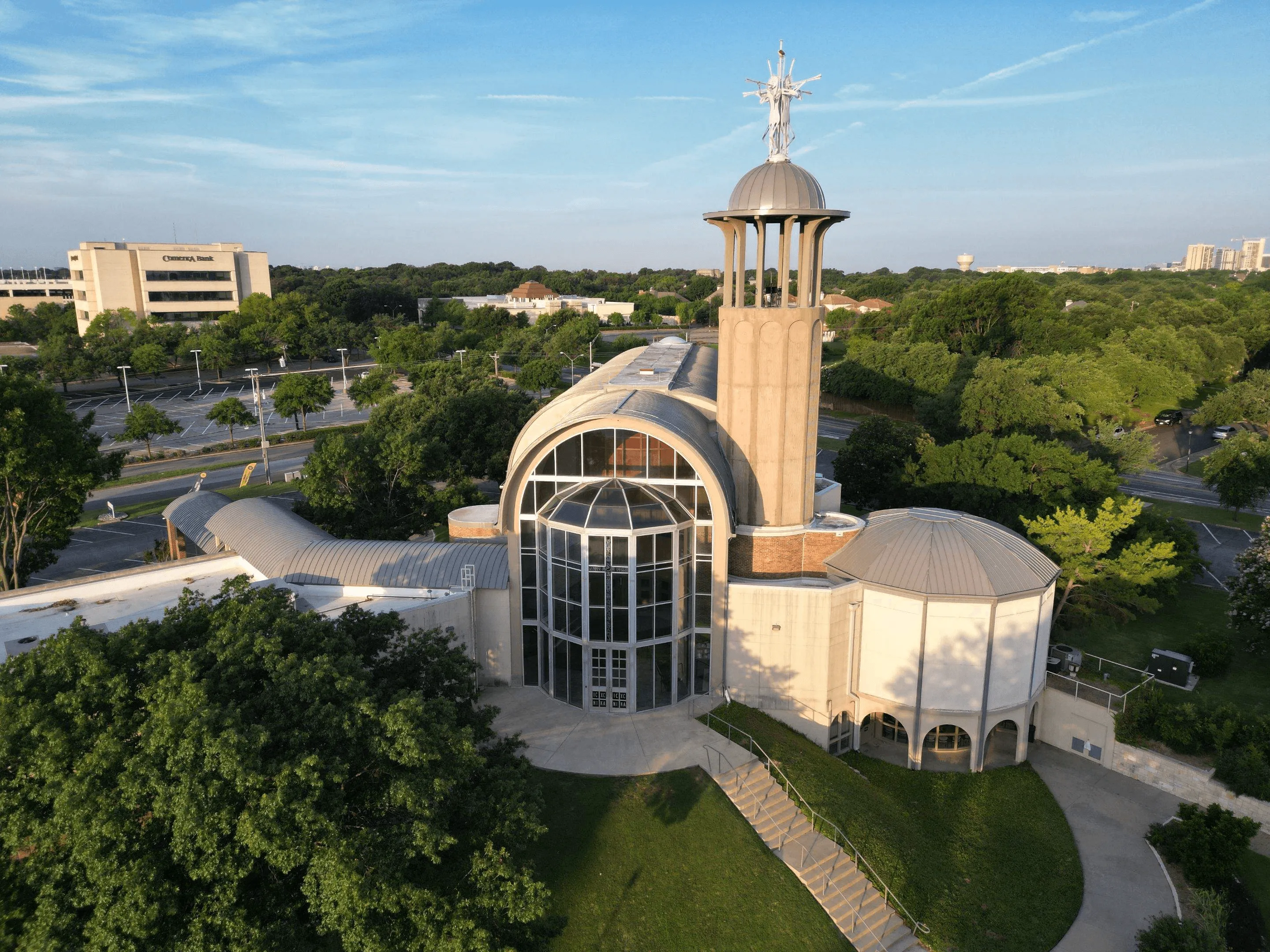 Large church with a tall cross-topped tower and arched glass entrance.