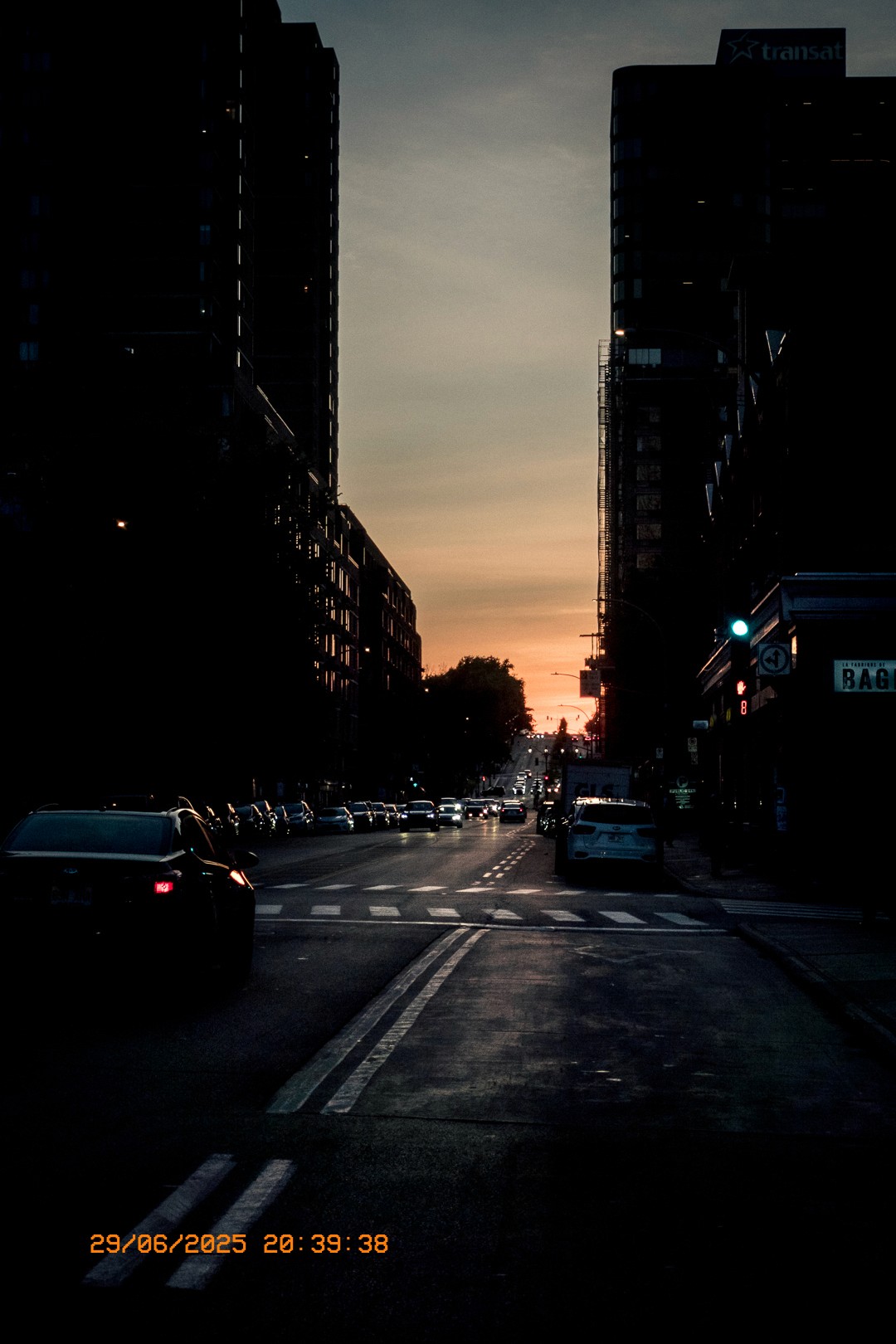 Rue de Montréal au crépuscule avec trafic et ciel orangé.