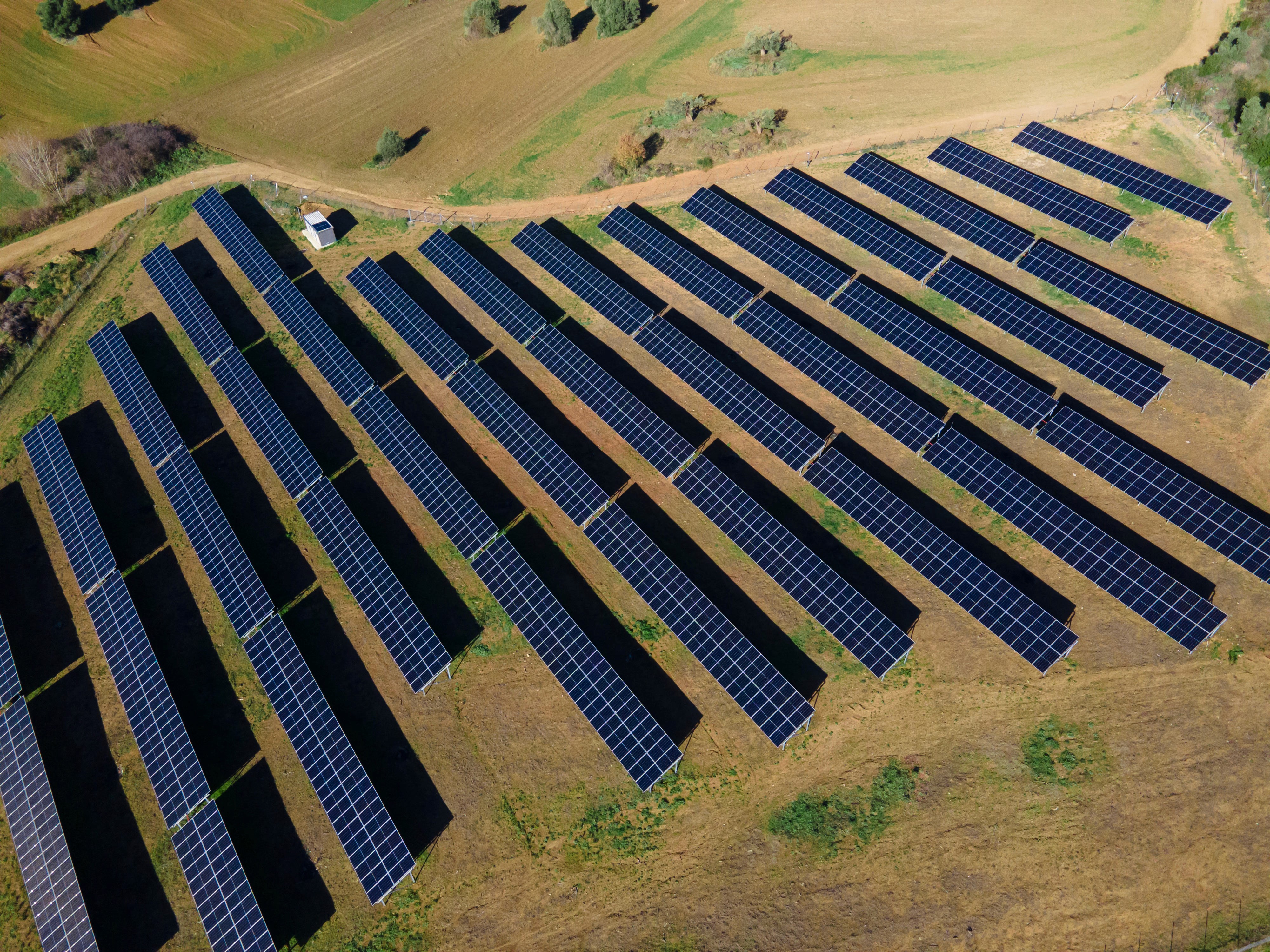 Aerial view of ground-mounted photovoltaic solar park installed across agricultural landscape