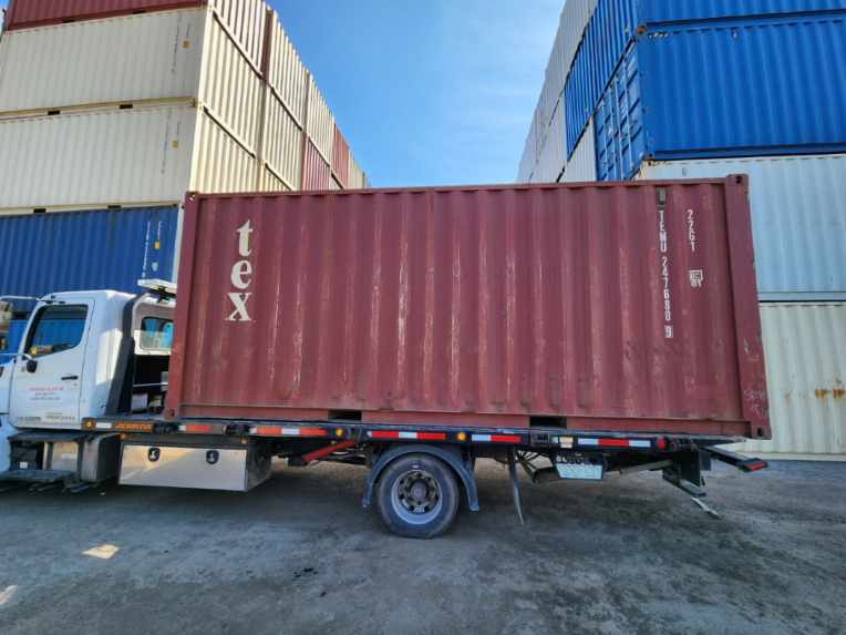 Used 20' container delivery in progress with tilt deck system