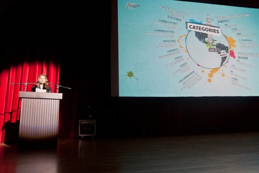 a woman is giving a presentation and next to her is a large image projected with the earth globe and some explanatory text around it