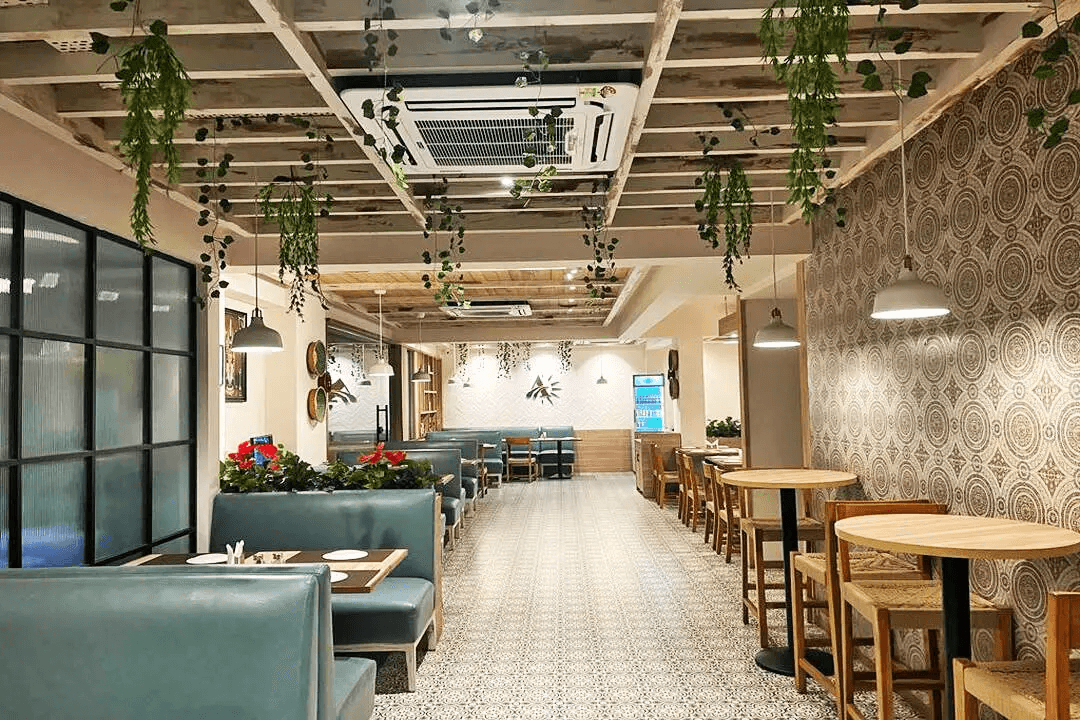 A modern cafe interior featuring wooden furniture, hanging plants, and a warm, inviting atmosphere.