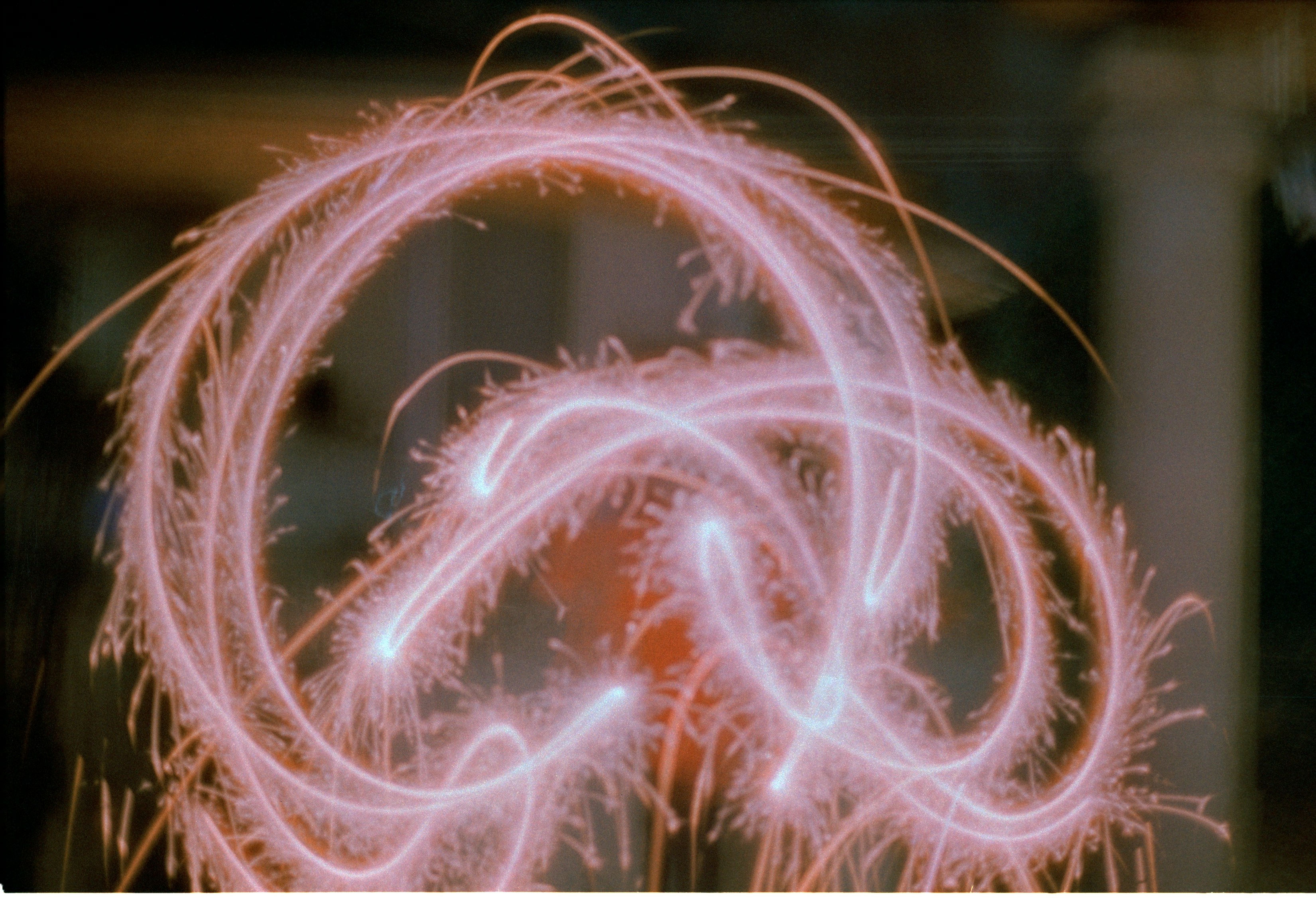 Pink light trails swirl in a chaotic pattern