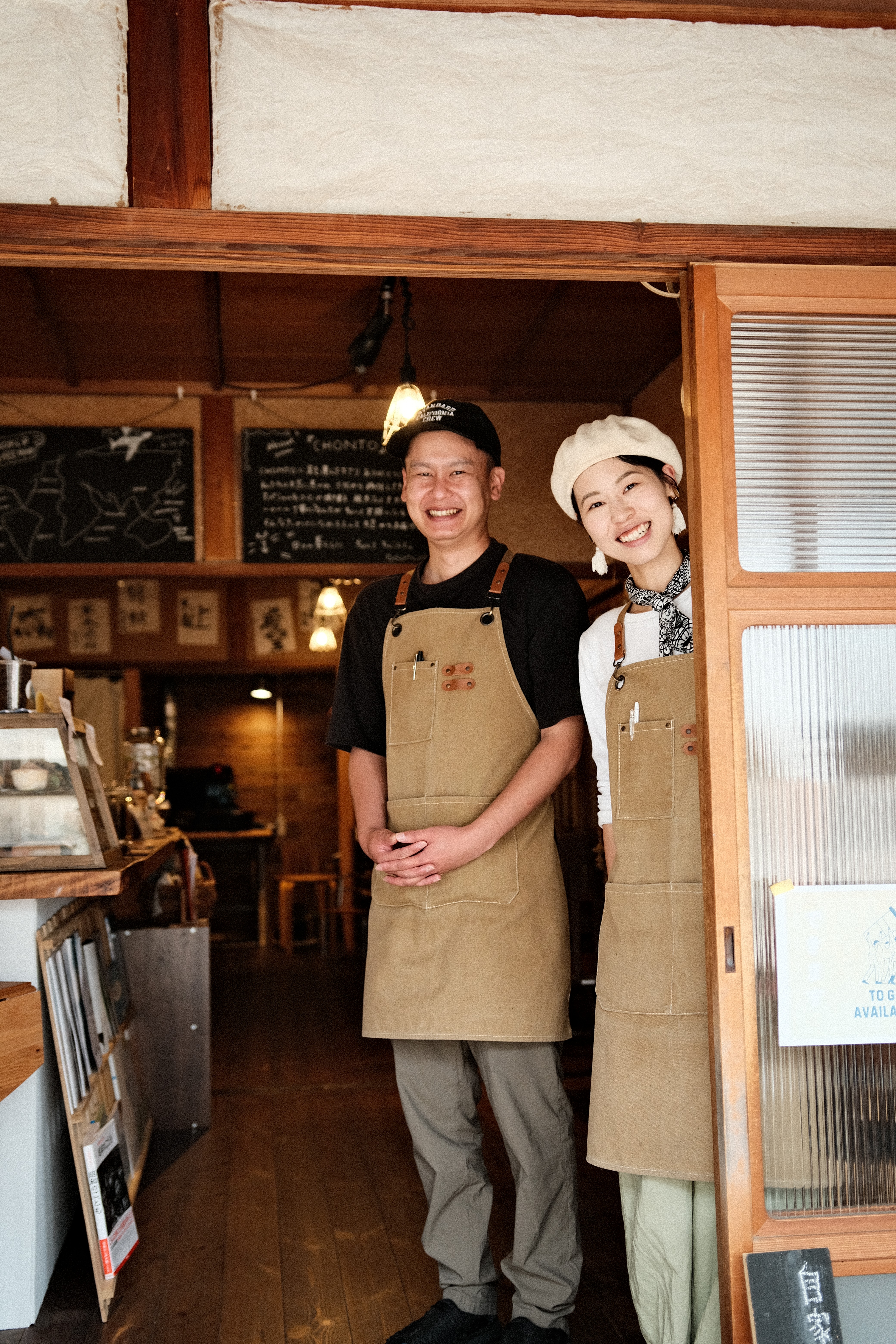 Japanese couple smiling in front of their cafe