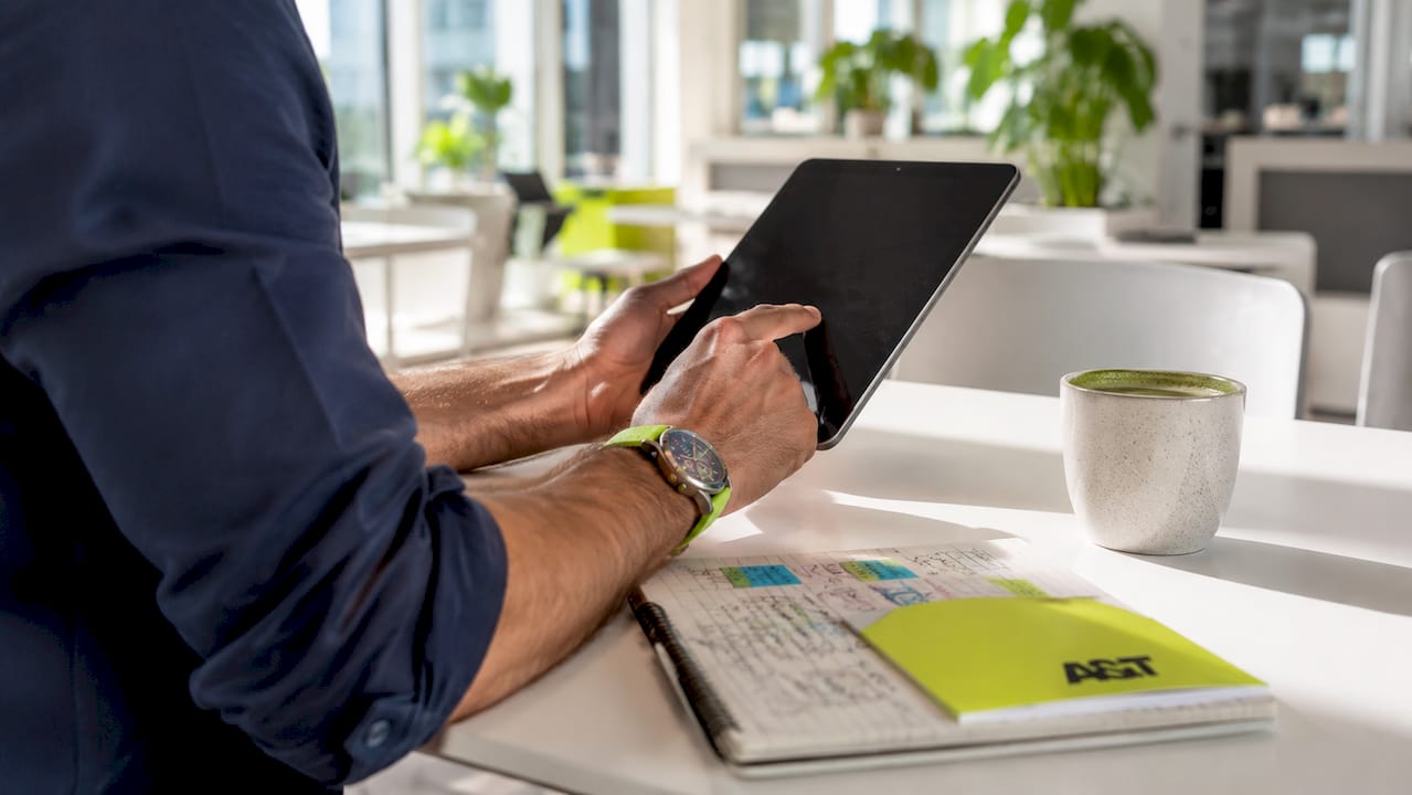 Hands scrolling competitor ad data on tablet at cafe table