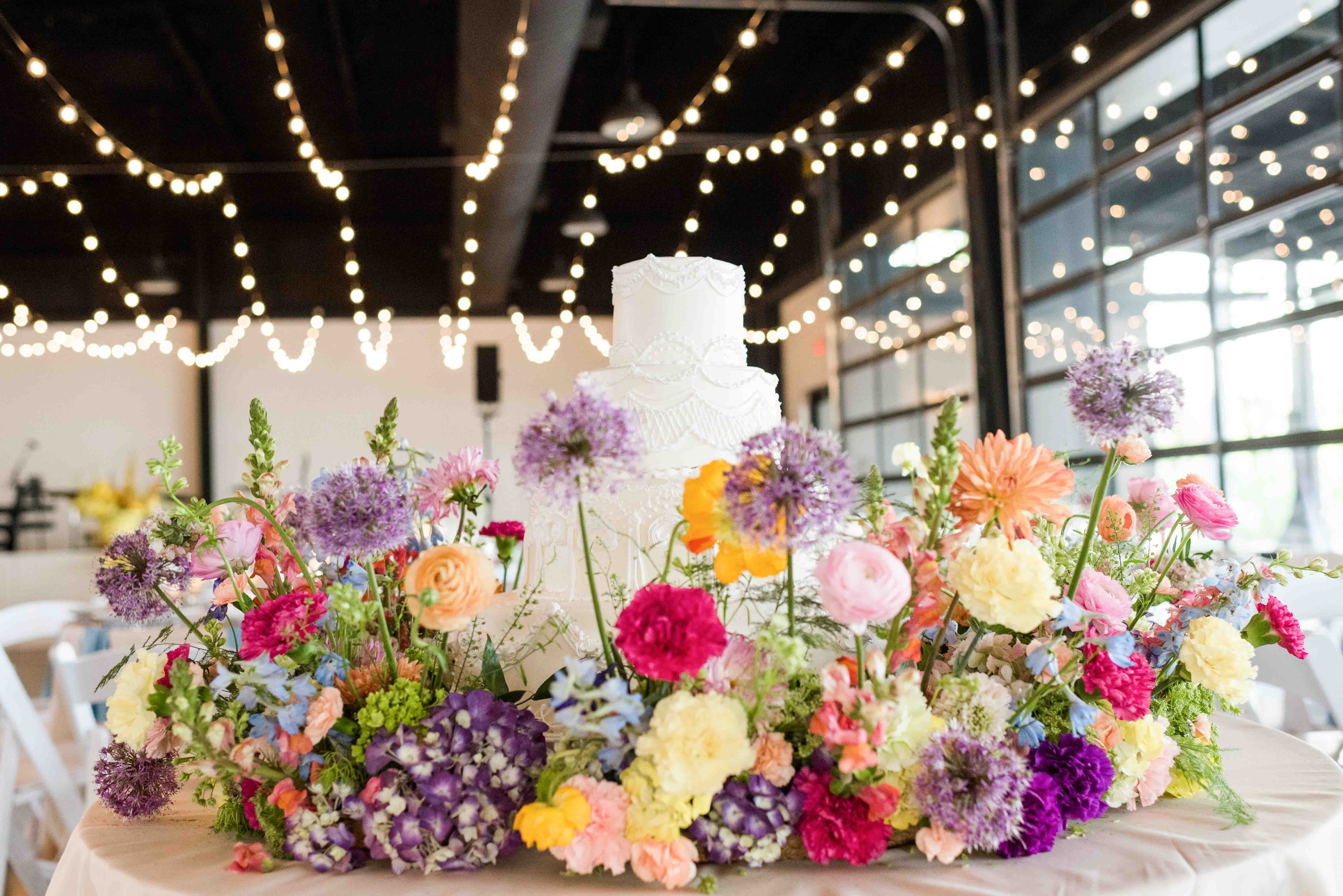 Wedding cake surrounded by colorful garden flowers.