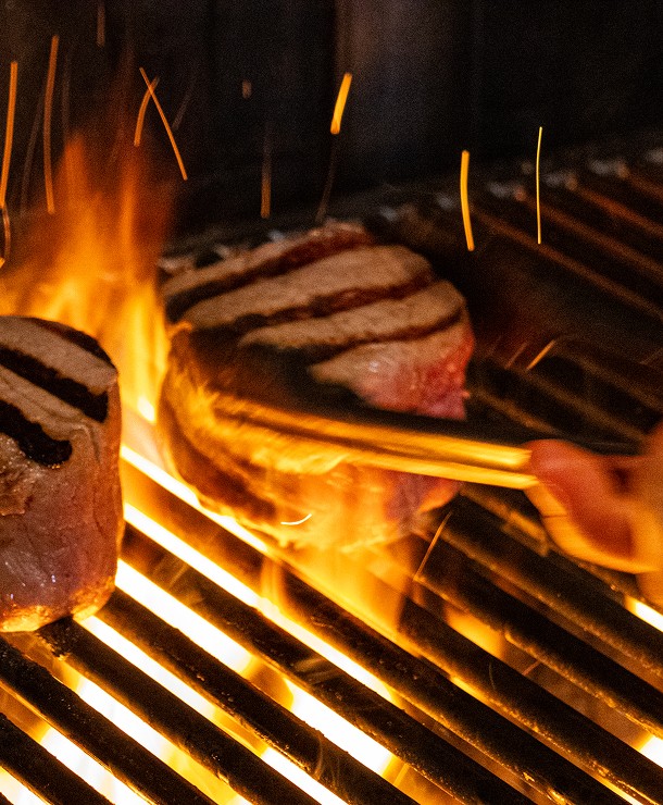 Příprava steaků na grilu s vysokými plameny