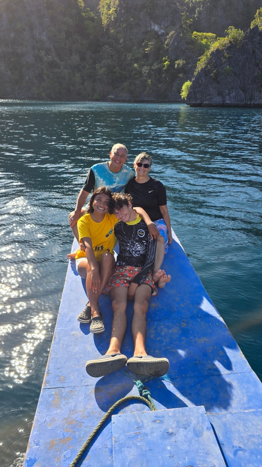 four boys laughing and sitting on grass during daytime