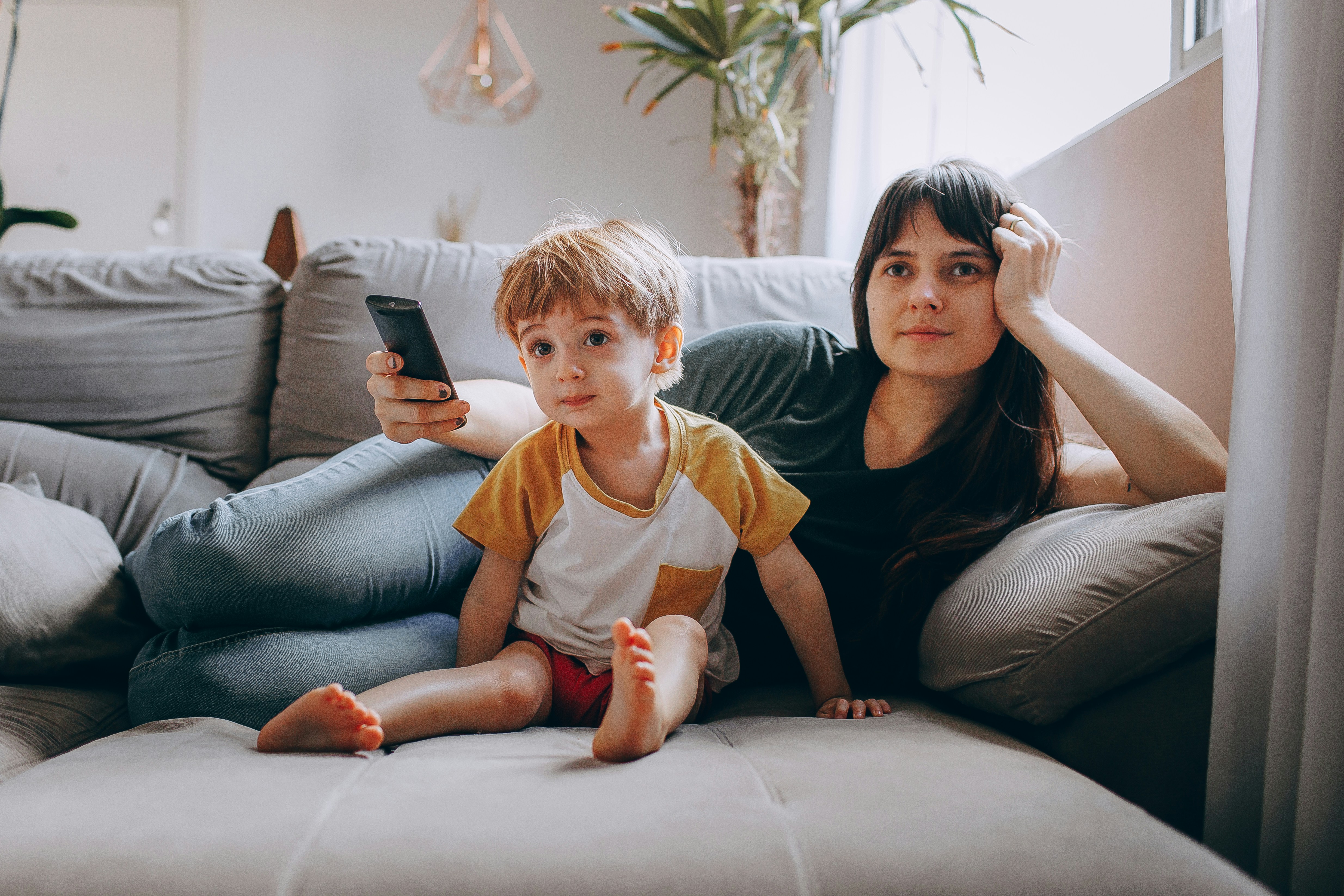 Mum sitting on the sofa using ChatGPT on her phone with her child 