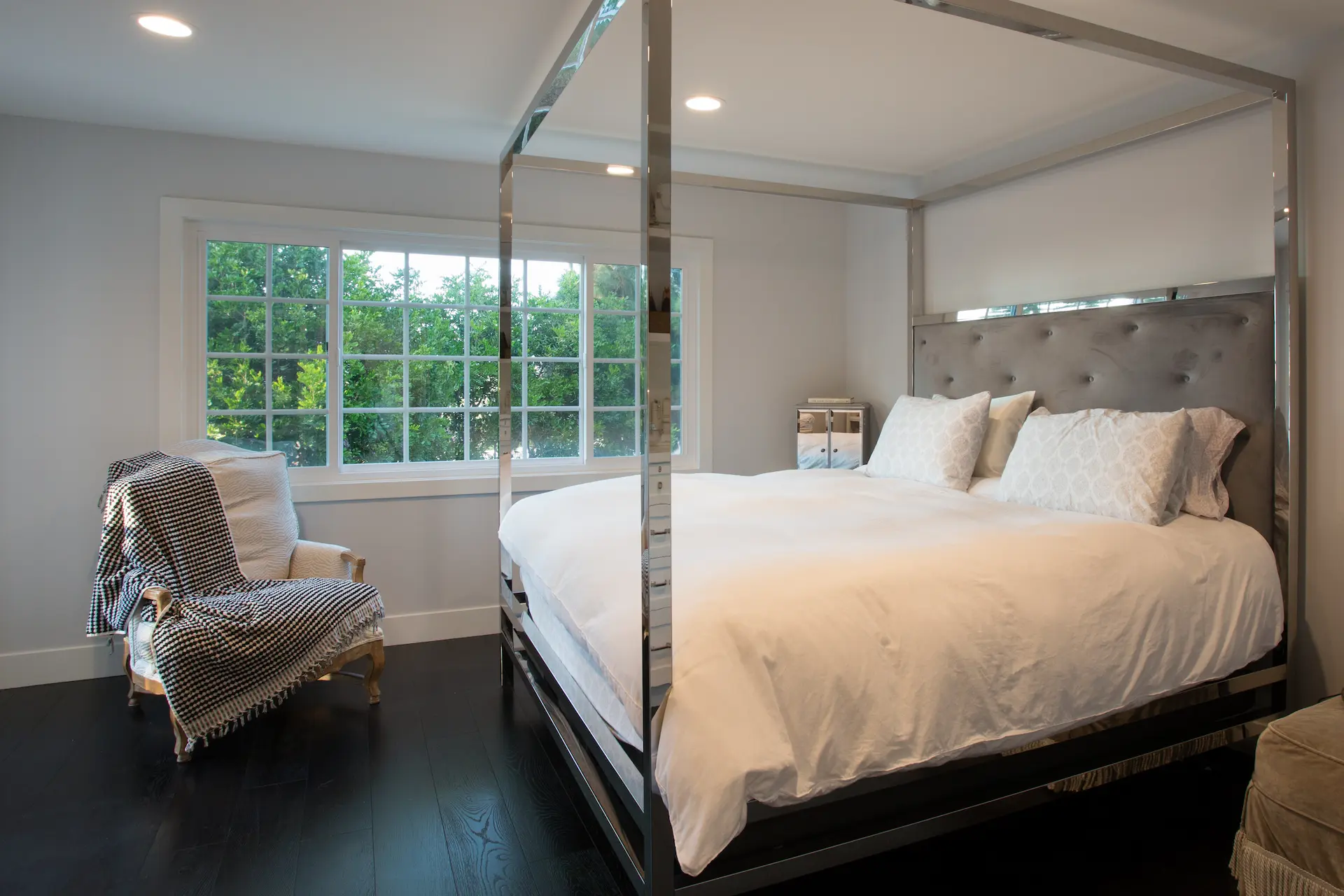 Elegan primary bedroom with modern chrome framed bed and white linens. From Dana Point Cape Cod remodel, photo by Chris Darnall.