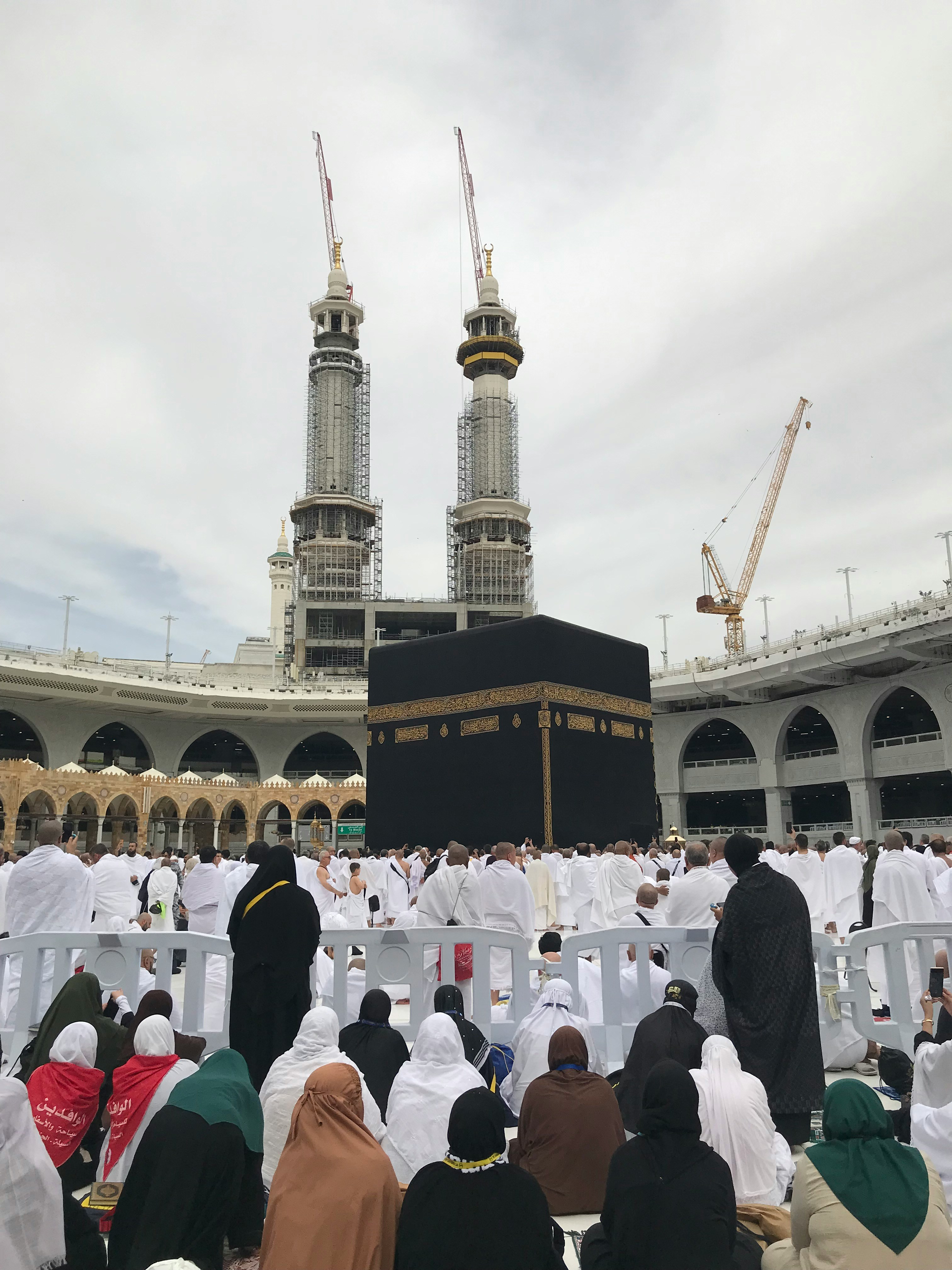 Large crowd of pilgrims in white robes surrounding the Kaaba in Mecca.