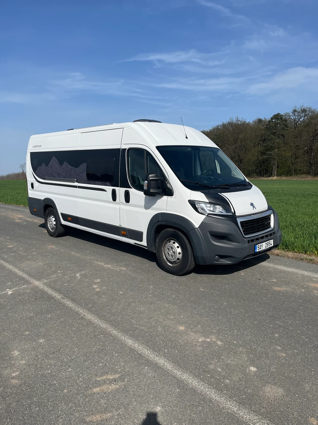 Bílý Peugeot Boxer L4H2 s horským motivem na boku, pohled zepředu a ze strany.
