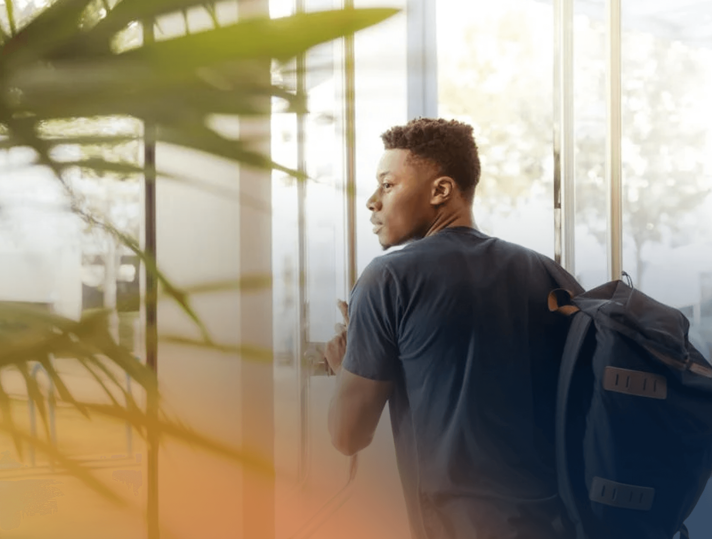 Man with rucksack exiting a glass office building door