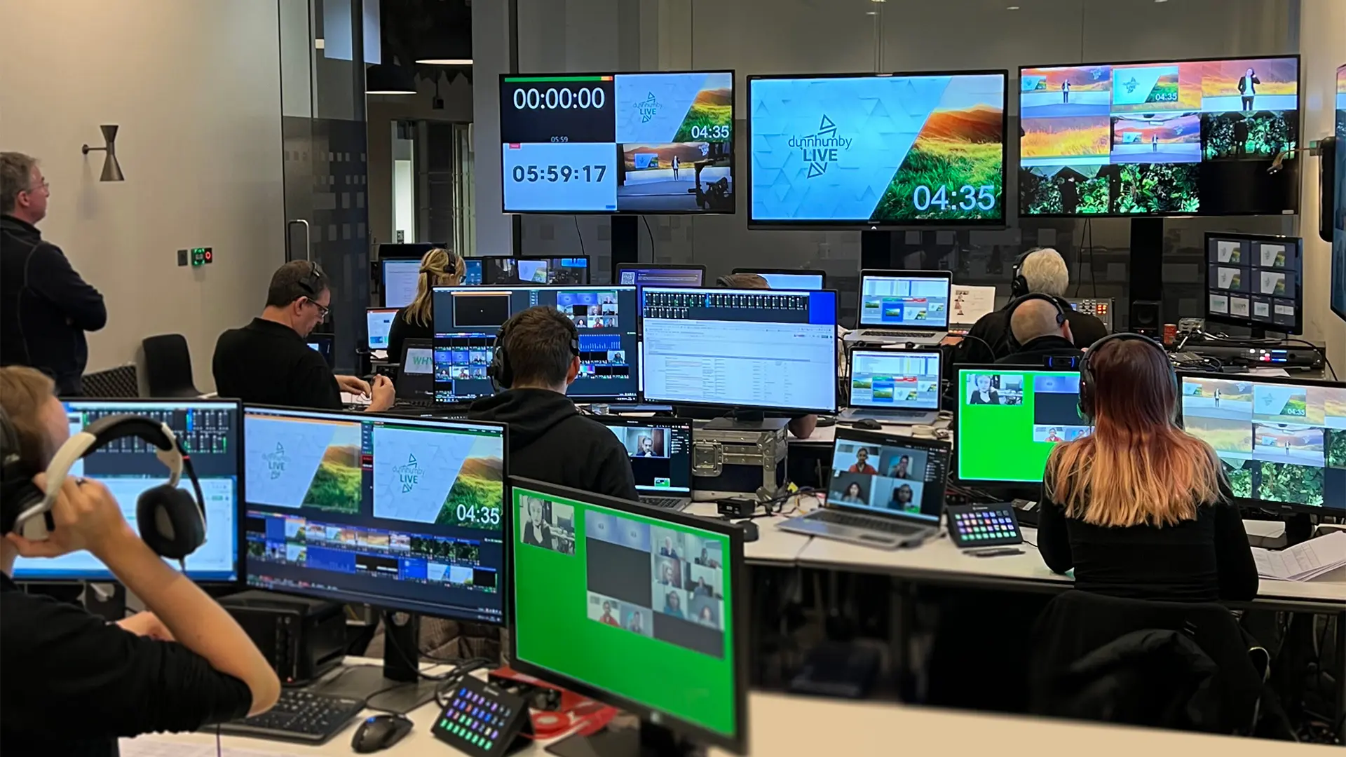 Control room filled with production staff monitoring multiple screens during a global live broadcast.
