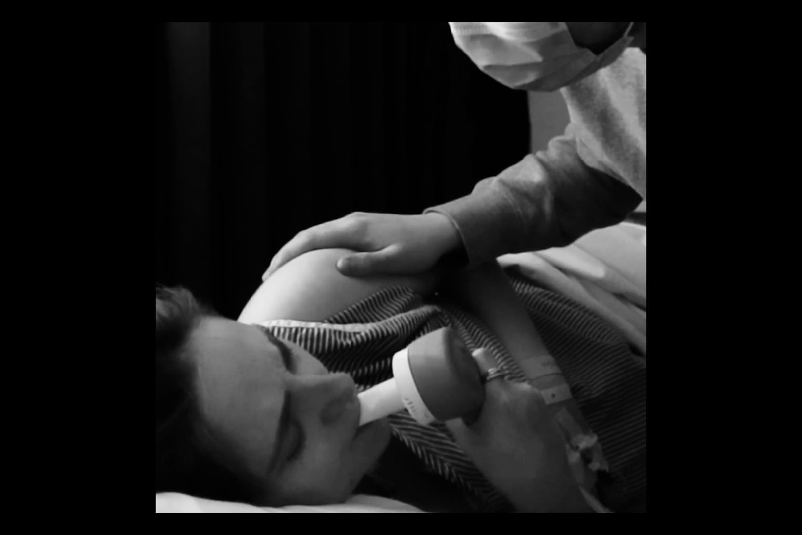 A black and white image of a woman on gas and air pain relief during child birth