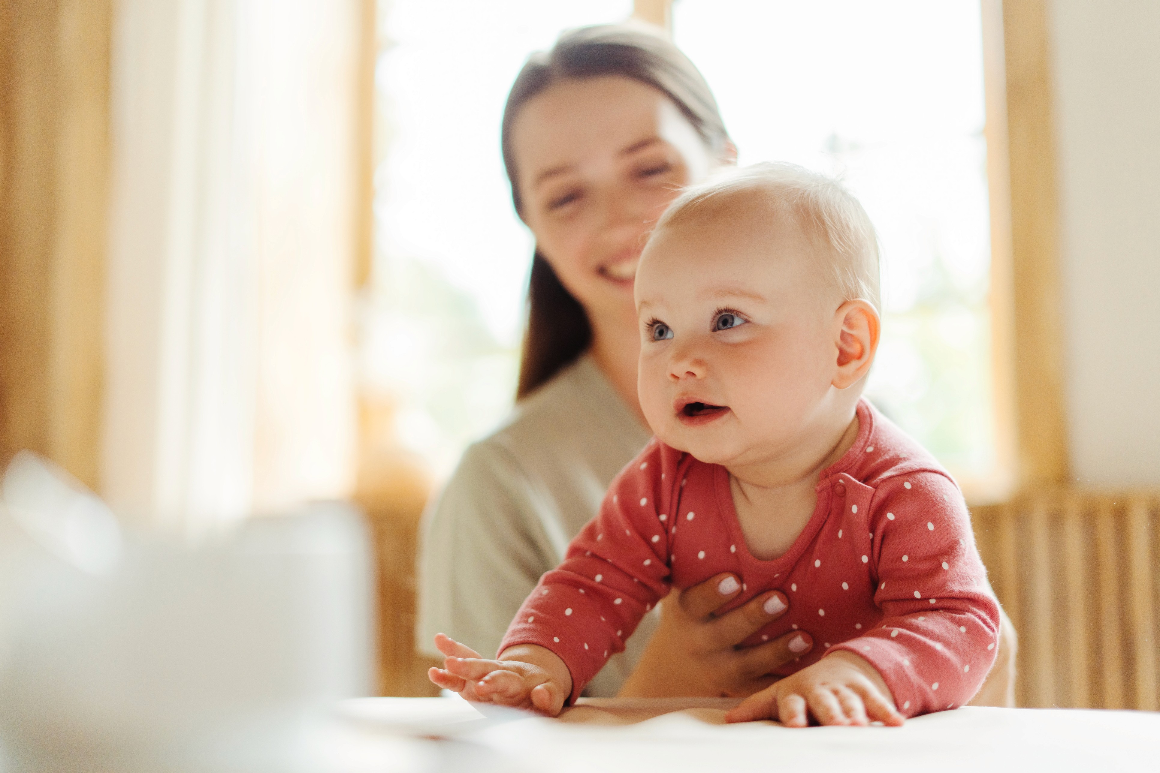 Ruhiger Moment: Schwangere sitzt am Tisch, lächelt, Hand auf dem Bauch – HR bestätigen weniger Ausfälle mit voiio – Familienservice.