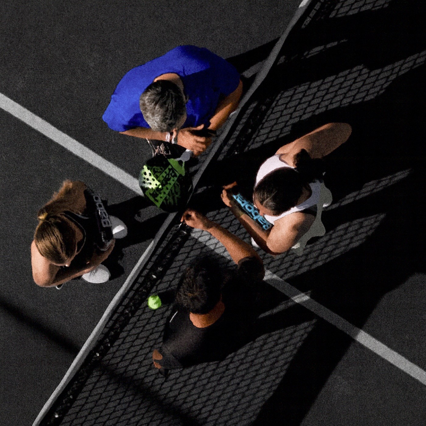 Vier Padelspieler treffen sich am Netz zu einem sportlichen Handschlag – Teamgeist, Fairplay und Gemeinschaft auf dem schwarzen Padelnero Court.