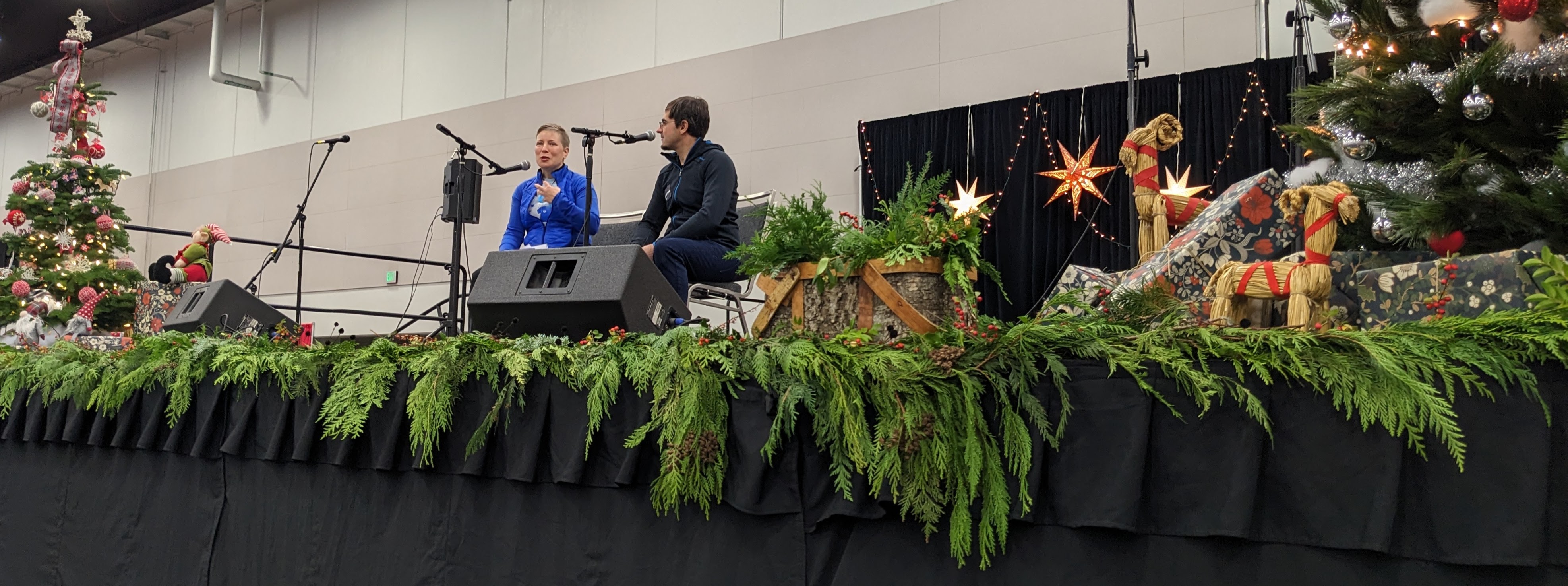 Photo of two people speaking on stage surrounded by Christmas decor