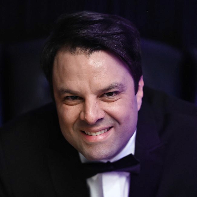 Profile portrait of a man in a white shirt against a light background