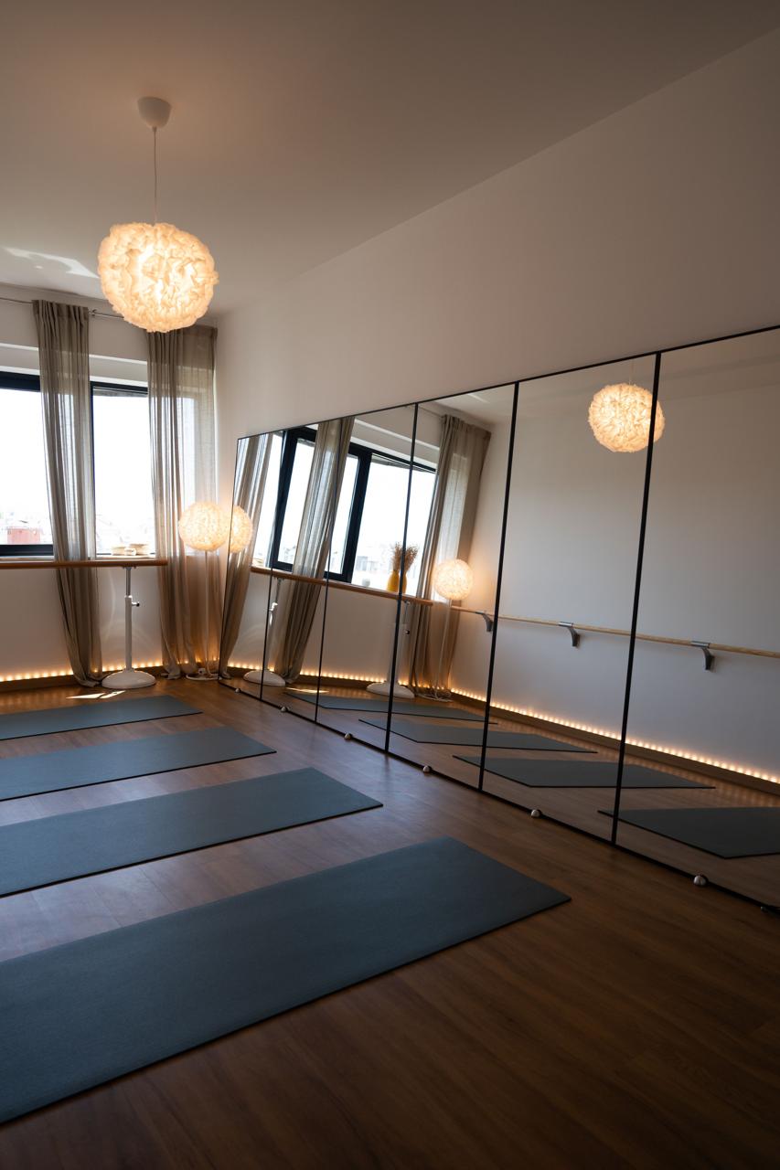 Warm and sunlit interior of the MokoBoko Mat Pilates and Barre studio in Saldanha, Lisbon, featuring dark mats and large mirrors for posture correction.