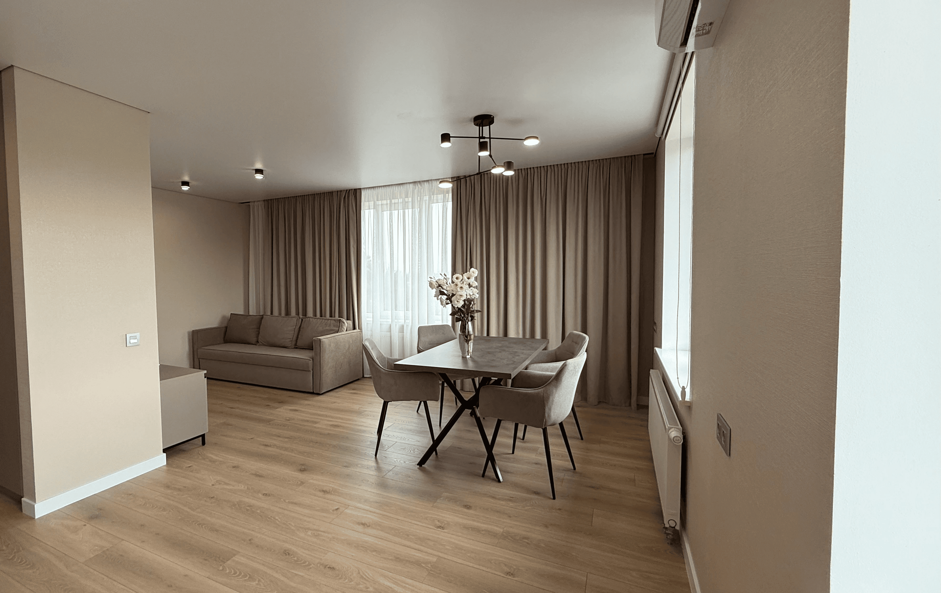 Вітальня з диваном, обіднім столом і великим вікном з фіранками