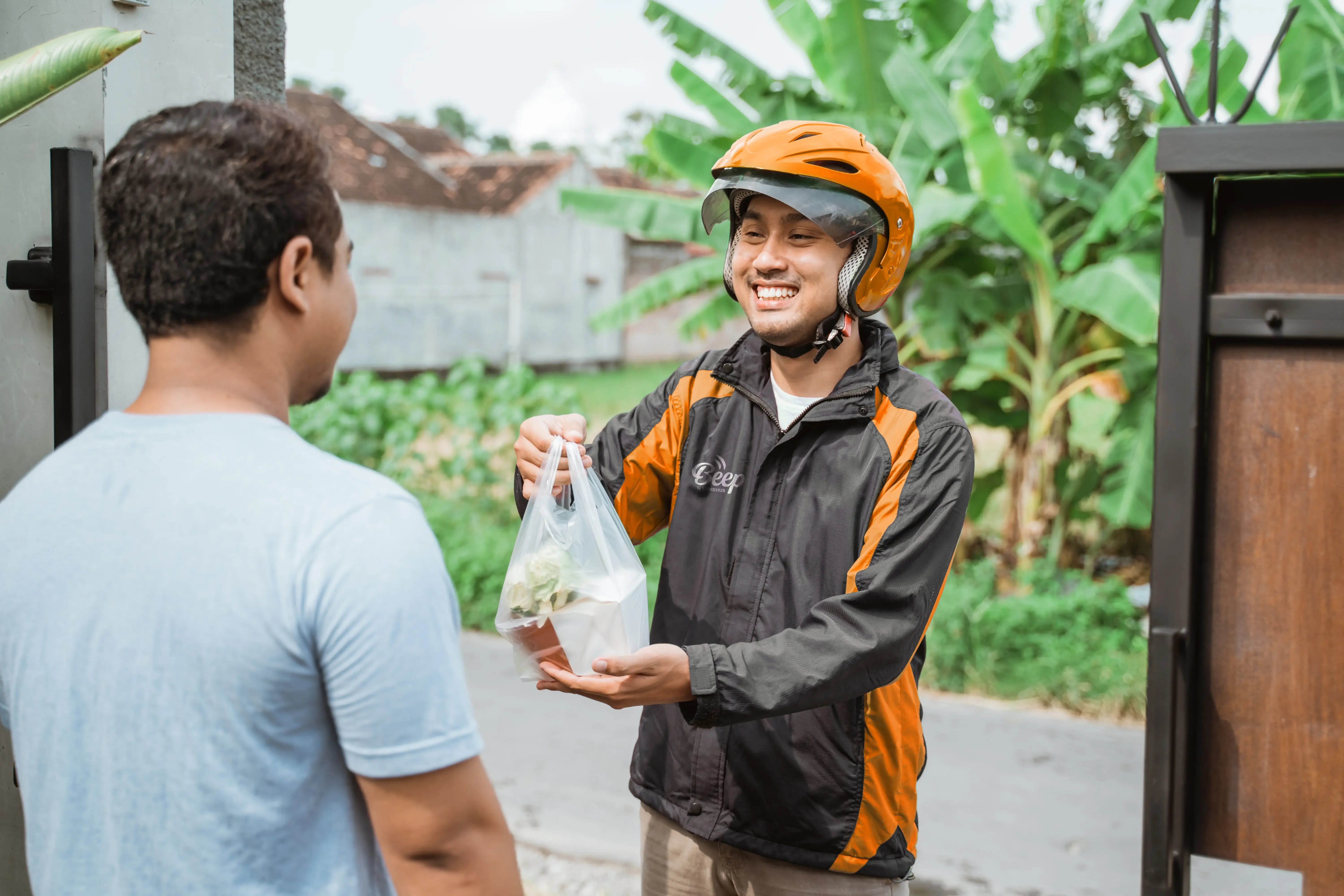 Malaysian cloud kitchen delivery rider delivering food to a customer, supported by the StoreHub POS system.