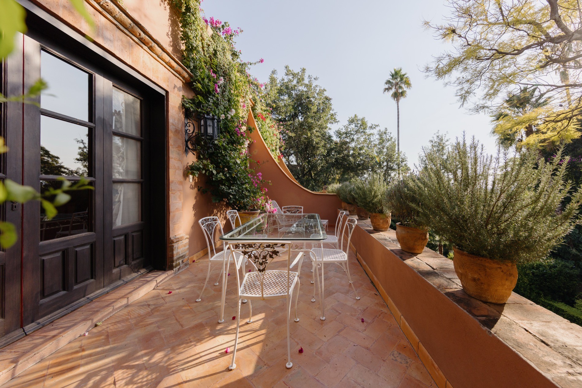 La Residencia sun-lit terrace with wrought iron seating and potted herbs