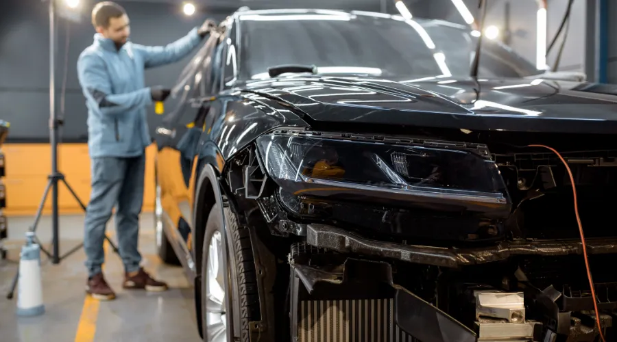 Man working on damaged car bumper and headlight